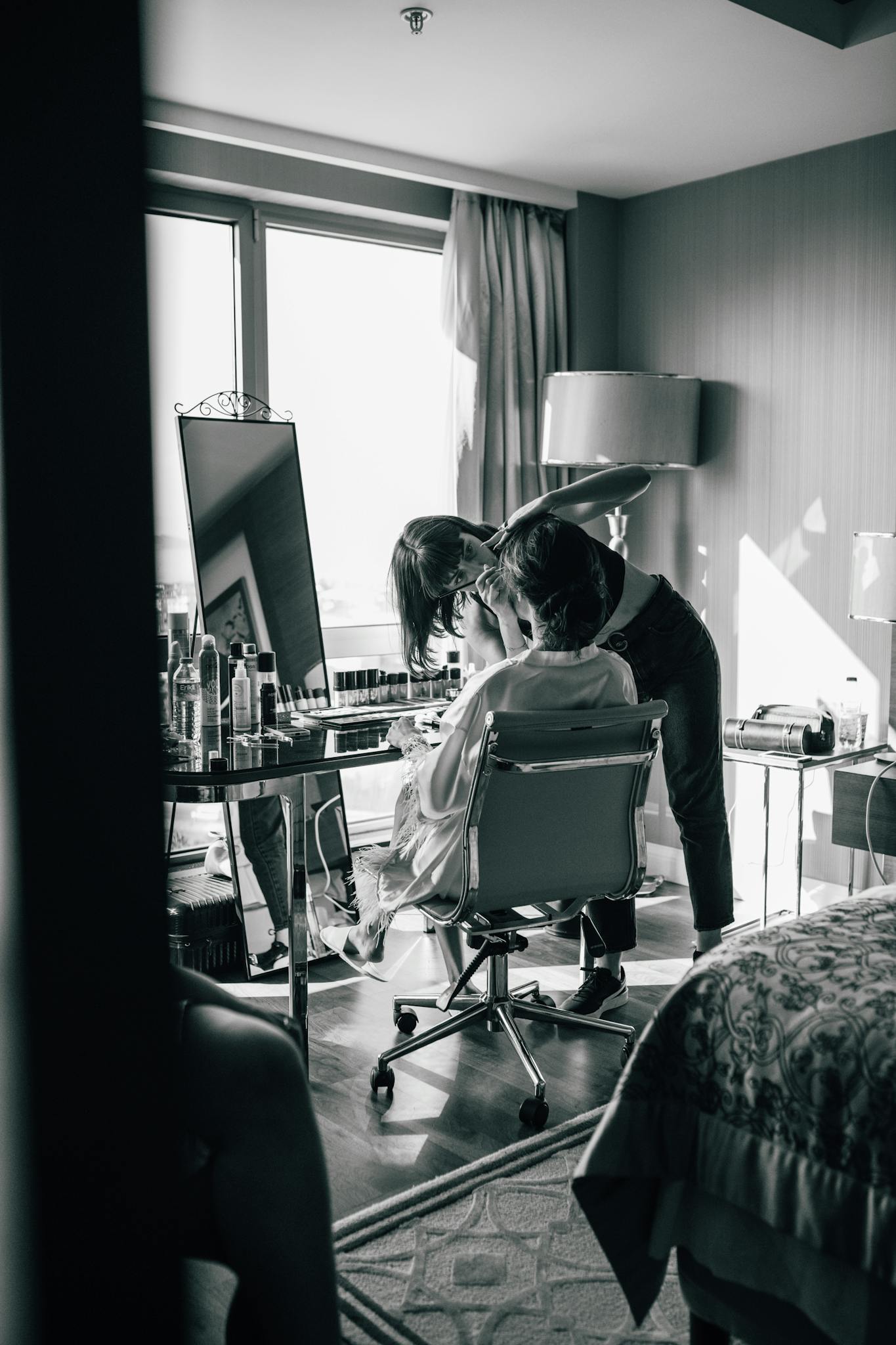 Bride getting makeup done in a hotel room, black and white style.